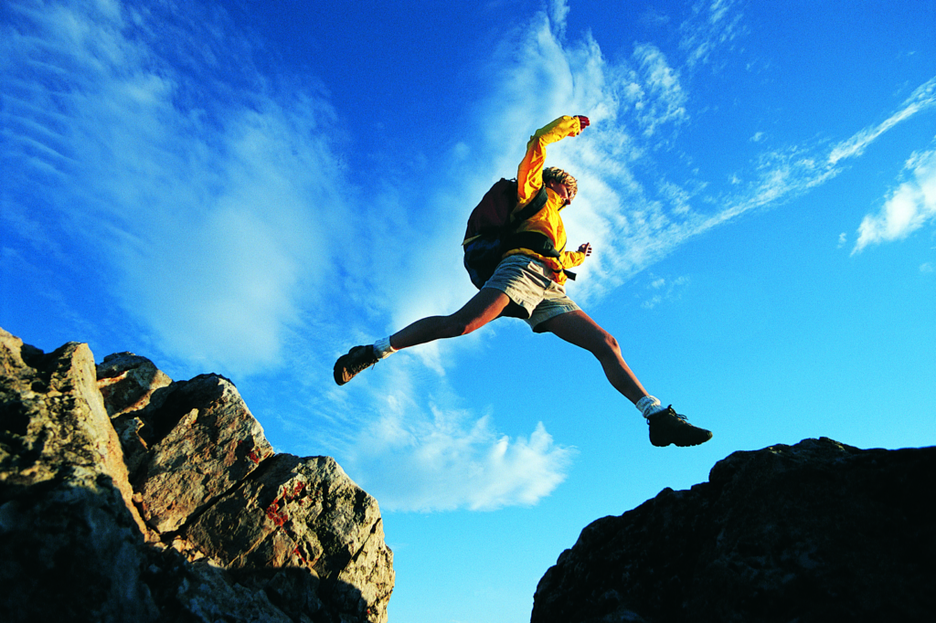 Man jumping across rocks while hiking